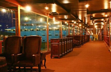 Vintage Luxury Yacht Hotel interior. Gay-friendly hotel lounge area with leather chairs, wooden floors, and glass windows. Upscale, unique stay.