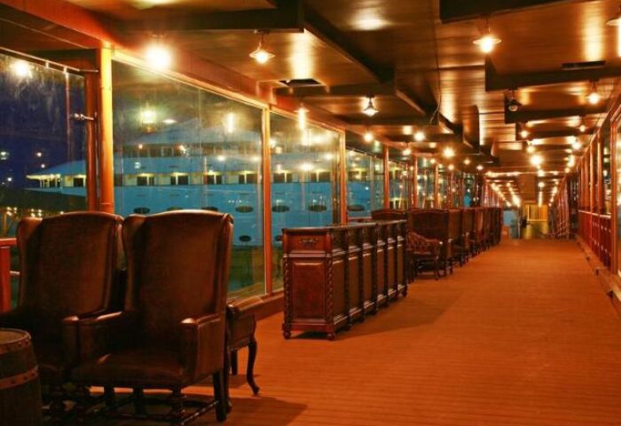 Vintage Luxury Yacht Hotel interior. Gay-friendly hotel lounge area with leather chairs, wooden floors, and glass windows. Upscale, unique stay.