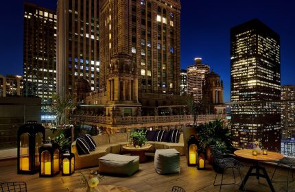 Rooftop lounge at night, Virgin Hotels Chicago, a gay-friendly hotel. City skyline view, cozy seating, and candlelit ambiance.