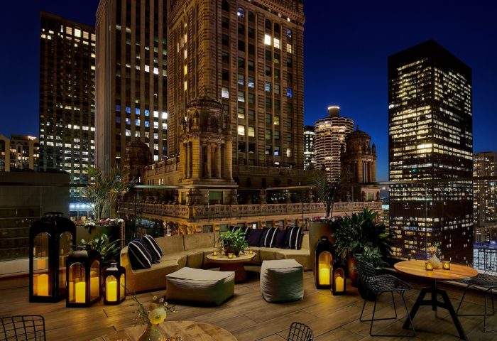 Rooftop lounge at night, Virgin Hotels Chicago, a gay-friendly hotel. City skyline view, cozy seating, and candlelit ambiance.