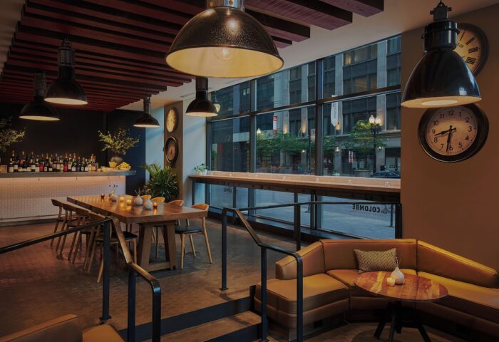 Gay-Friendly Virgin Hotels Chicago interior. Bar, dining table, and lounge area. Modern design, urban view. Great for gay travel in Chicago.