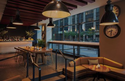 Gay-Friendly Virgin Hotels Chicago interior. Bar, dining table, and lounge area. Modern design, urban view. Great for gay travel in Chicago.