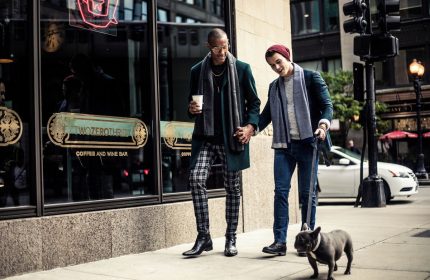 Gay couple holds hands outside Virgin Hotels Chicago with their dog. Gay-Friendly hotel for gay men travel advice in Chicago.