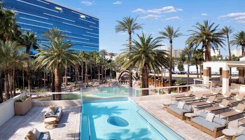 Virgin Hotels Las Vegas, Curio Collection by Hilton pool area. Gay-friendly hotel with palm trees and blue sky. Las Vegas travel.