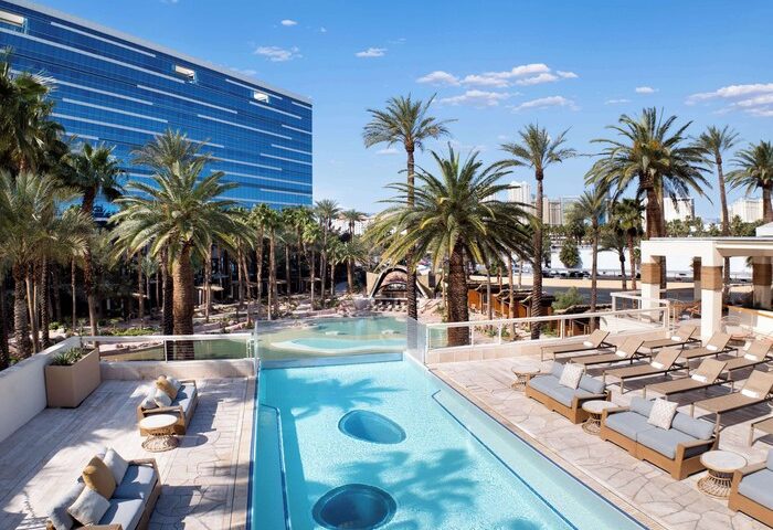 Virgin Hotels Las Vegas, Curio Collection by Hilton pool area. Gay-friendly hotel with palm trees and blue sky. Las Vegas travel.