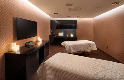 Spa room at gay-friendly Virgin Hotels Las Vegas, Curio Collection by Hilton. Two massage beds, TV, candles, and sink area.