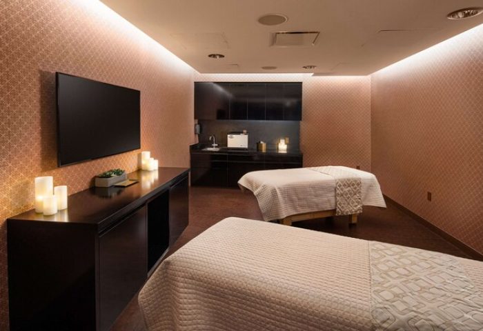 Spa room at gay-friendly Virgin Hotels Las Vegas, Curio Collection by Hilton. Two massage beds, TV, candles, and sink area.