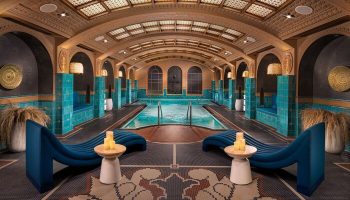 Indoor pool area at Virgin Hotels Las Vegas, Curio Collection by Hilton. Gay-friendly hotel with lounge chairs and decorative tile.