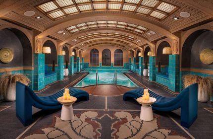 Indoor pool area at Virgin Hotels Las Vegas, Curio Collection by Hilton. Gay-friendly hotel with lounge chairs and decorative tile.