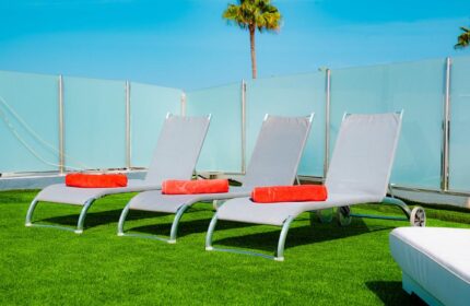 Vista Bonita Gay Resort: Sun loungers with towels on green turf. Relax at this gay-friendly hotel. Palm tree and blue sky in background.