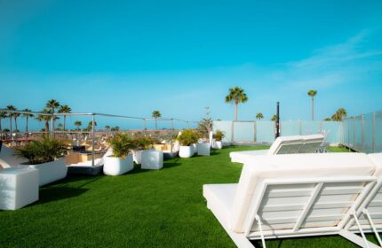 Vista Bonita Gay Resort rooftop. White loungers, planters, and green turf under a clear blue sky. Gay-friendly hotel for men's travel.