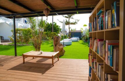 Vista Bonita Gay Resort's outdoor lounge area. Bookshelf, wooden table, and lawn with sunbeds. A gay-friendly hotel for a relaxing vacation.