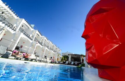 Vista Bonita Gay Resort pool view. Gay-friendly hotel with modern design, pool, and red sculpture. Ideal for gay men's travel.
