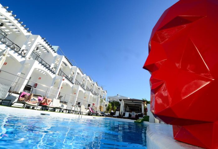 Vista Bonita Gay Resort pool view. Gay-friendly hotel with modern design, pool, and red sculpture. Ideal for gay men's travel.