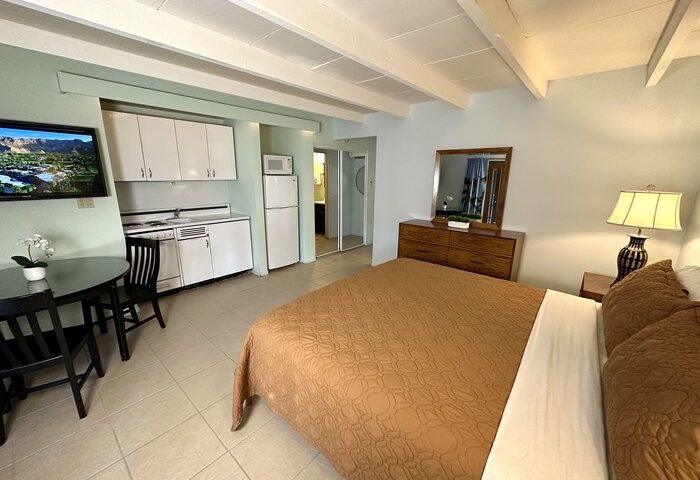 Vista Grande Resort room. Gay men's resort features a bed, kitchenette, table, TV, dresser, and bathroom. Gay-friendly hotel.
