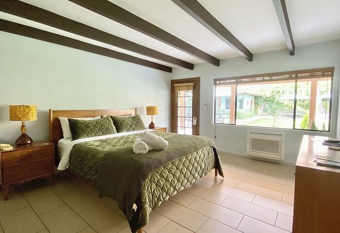 Bedroom at Vista Grande Resort, a gay men's resort. Room with bed, beams, and view to the garden. Gay-friendly hotel for men's travel.