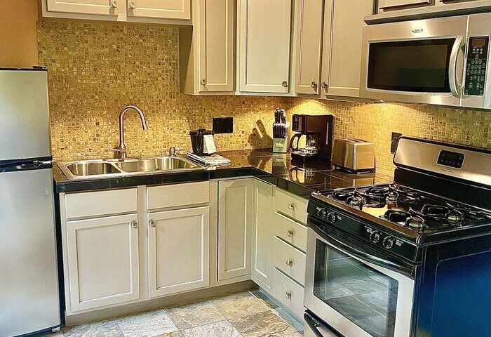 Kitchen at Vista Grande Resort, a gay men's resort. Features include a stove, microwave, refrigerator, sink, and tiled floor. Gay-friendly hotel.
