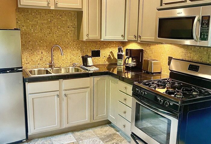 Kitchen at Vista Grande Resort, a gay men's resort. Features include a stove, microwave, refrigerator, sink, and tiled floor. Gay-friendly hotel.