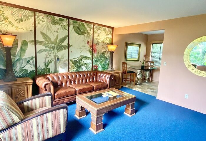 Vista Grande Resort, a gay men's resort: Living area with leather sofa, tropical mural, blue carpet. Gay-friendly hotel interior.