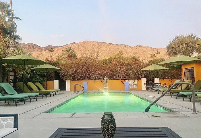 Vista Grande Resort's pool, a gay men's resort. Mountains in the background. Gay-friendly hotel with lounge chairs and umbrellas.
