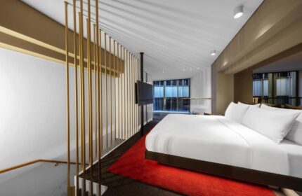 W Amsterdam gay-friendly hotel room. Modern design with gold accents, red rug, and large bed. A luxurious stay for gay travelers in Amsterdam.