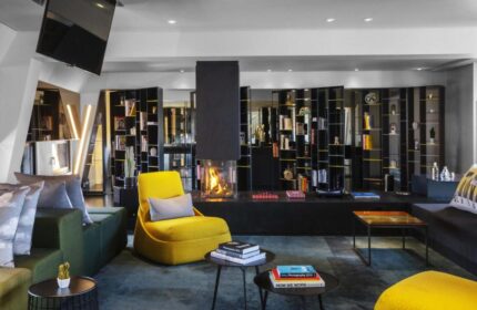 W Amsterdam gay-friendly hotel lounge area with fireplace, bookshelves, and stylish seating. A modern, welcoming space for gay travelers.