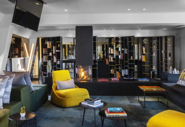 W Amsterdam gay-friendly hotel lounge area with fireplace, bookshelves, and stylish seating. A modern, welcoming space for gay travelers.