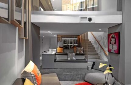W Amsterdam gay-friendly hotel room. Modern design with a loft, sofa, red rug, and stylish decor. Luxury gay travel in Amsterdam.
