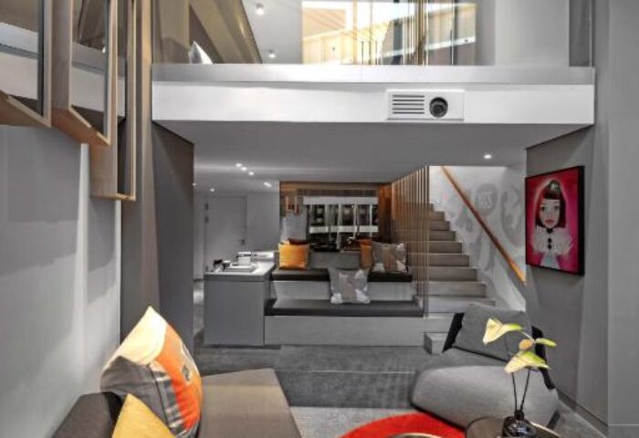 W Amsterdam gay-friendly hotel room. Modern design with a loft, sofa, red rug, and stylish decor. Luxury gay travel in Amsterdam.
