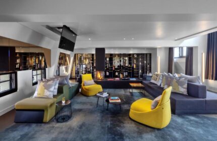 W Amsterdam gay-friendly hotel lounge area with modern design, sofas, chairs, fireplace, and TV. Upscale interior for gay travelers.