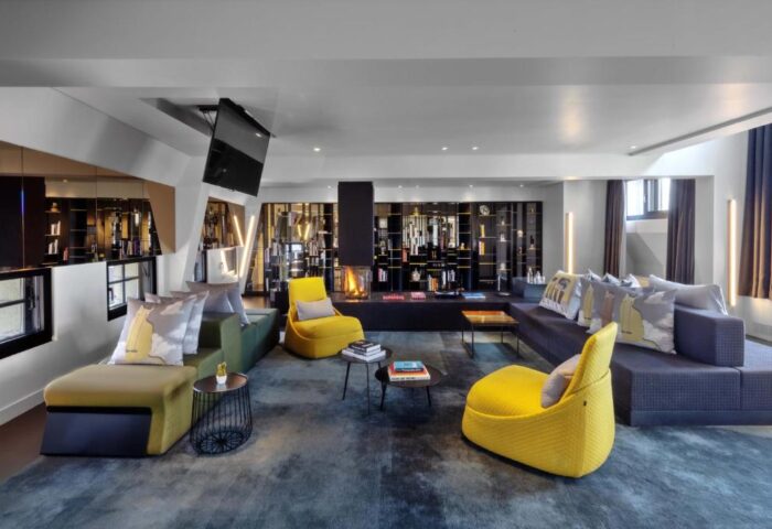 W Amsterdam gay-friendly hotel lounge area with modern design, sofas, chairs, fireplace, and TV. Upscale interior for gay travelers.