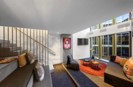 Interior of Gay-Friendly Hotel W Amsterdam. Modern design with seating area, staircase, and artwork. Bright, open space with natural light.