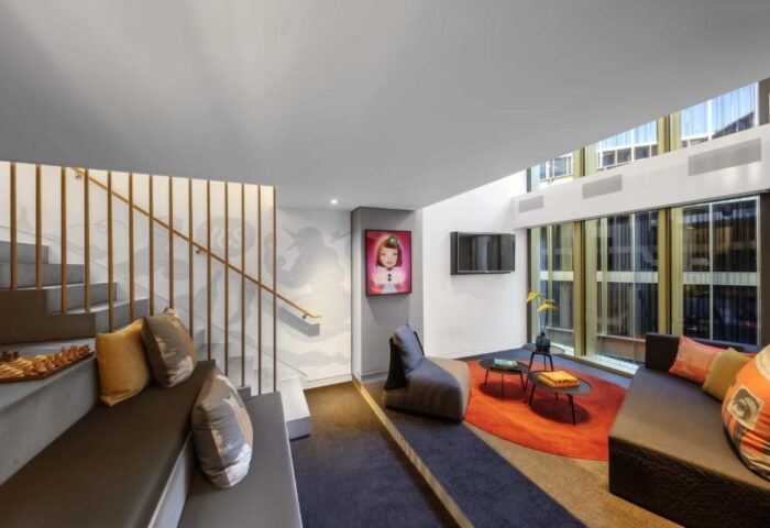 Interior of Gay-Friendly Hotel W Amsterdam. Modern design with seating area, staircase, and artwork. Bright, open space with natural light.