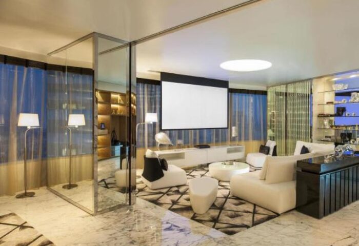 W Bangkok, a gay-friendly & pet-friendly hotel. Modern suite interior with white furniture, projector screen, and marble floors. Luxury travel.