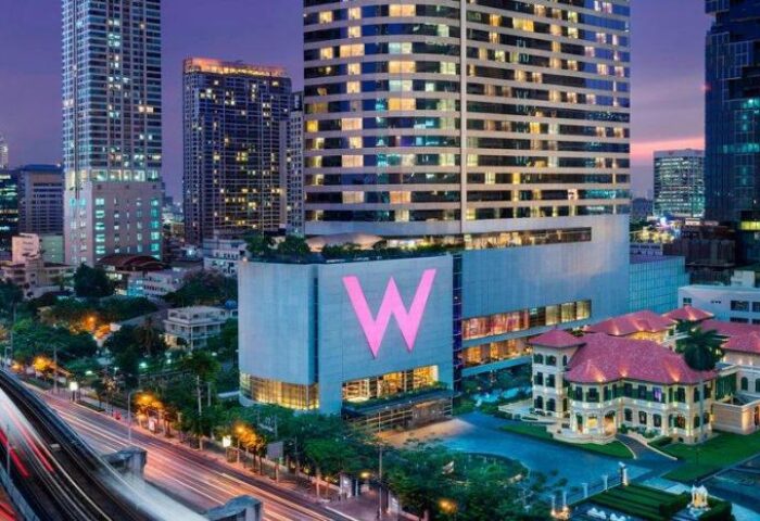 W Bangkok, a gay-friendly and pet-friendly hotel. Exterior view of the hotel with a large pink W logo, skyscrapers, and city lights.