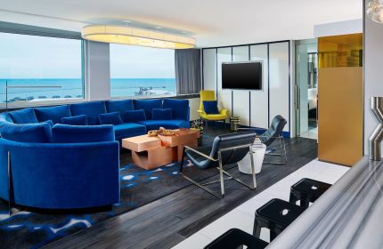 W Chicago Lakeshore gay-friendly hotel room. Modern design with blue sofa, lake view. Luxury travel for gay men in Chicago.