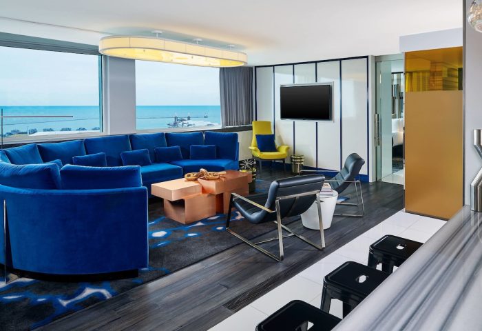 W Chicago Lakeshore gay-friendly hotel room. Modern design with blue sofa, lake view. Luxury travel for gay men in Chicago.