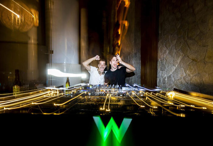 Gay-friendly W Koh Samui hotel: Two DJs perform with energy behind the decks, illuminated by the W logo. Nightlife at this pet-friendly resort.