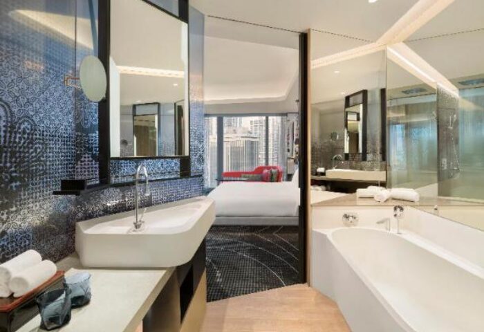 W Kuala Lumpur gay-friendly hotel room. Modern bathroom with tub, sink, and mirror. Bedroom with city view. Luxury travel for gay men.