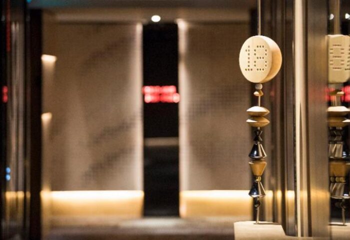 Interior detail at W Kuala Lumpur, a gay-friendly hotel. Ornate wooden sculpture hangs near the entrance. Luxury travel for gay men.