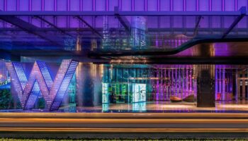 W Kuala Lumpur gay-friendly hotel entrance at night. The W Hotel's illuminated 'W' logo and vibrant purple lighting create a modern, stylish vibe.