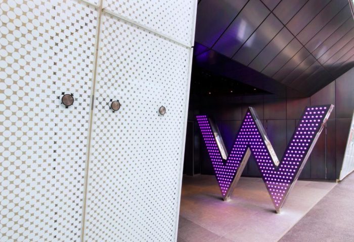 W London Leicester Square entrance. Gay-friendly, pet-friendly hotel. Exterior view with the iconic W logo illuminated in purple.