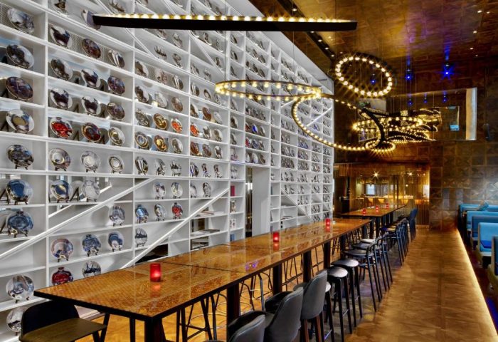 Interior of W London Leicester Square, a gay-friendly, pet-friendly hotel. Wall with plates, tables, and lights.