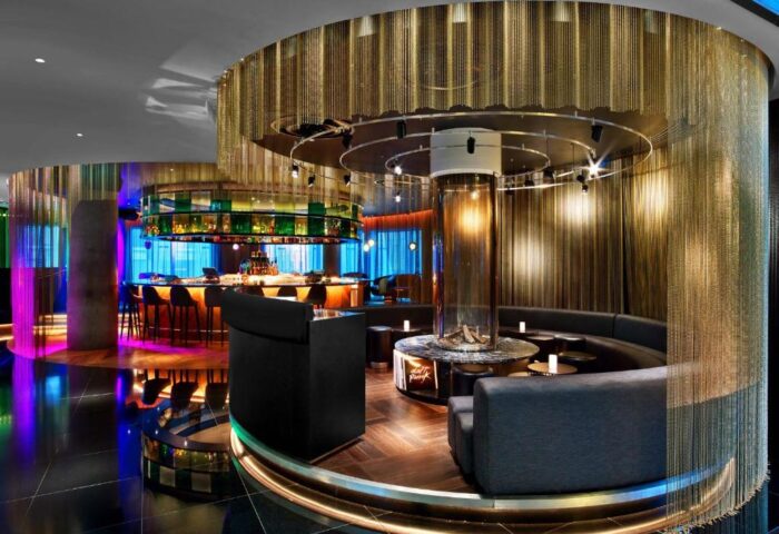 W London Leicester Square gay-friendly hotel bar. Modern design with circular seating, a central fireplace, and colorful lighting. Pet-friendly.