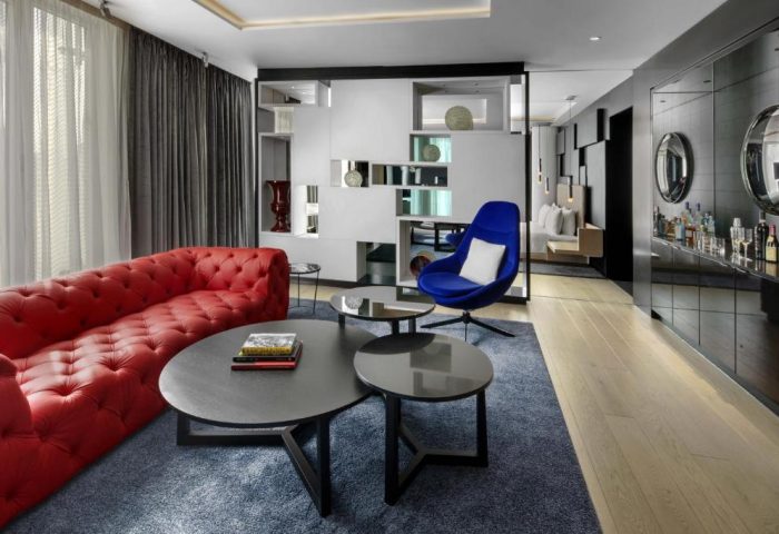 W London Leicester Square hotel room. Red sofa, blue chair, and modern decor. Gay-friendly, pet-friendly hotel interior.