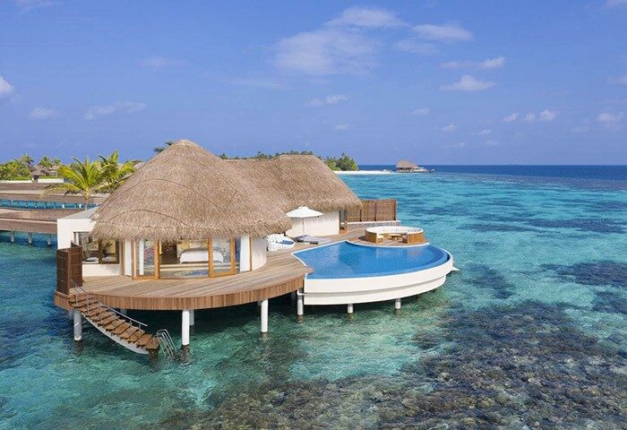 Gay-friendly W Maldives hotel overwater bungalow. Thatched roof villa with private pool. Luxury travel for gay men in the Maldives.