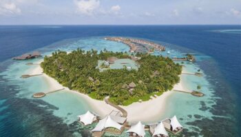 Aerial view of W Maldives, a gay-friendly hotel. Tropical island with palm trees, white sand beaches, overwater bungalows. Perfect for LGBTQ+ travel.