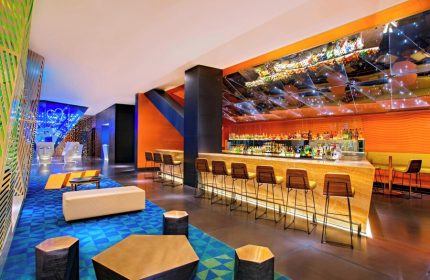 W Mexico City gay-friendly hotel bar interior. Stylish design with vibrant colors, modern furniture, and a well-stocked bar. Perfect for gay travelers.