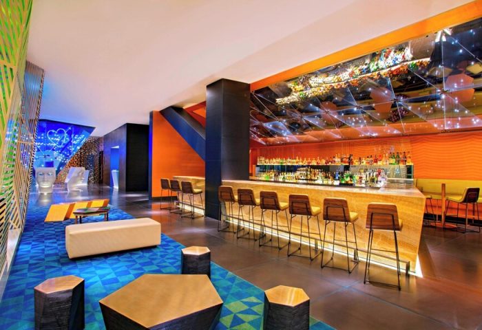 W Mexico City gay-friendly hotel bar interior. Stylish design with vibrant colors, modern furniture, and a well-stocked bar. Perfect for gay travelers.