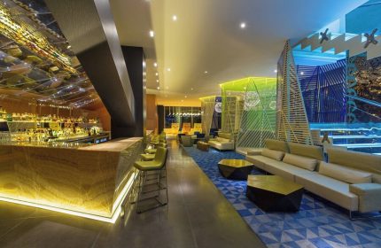 W Mexico City gay-friendly hotel bar and lounge area. Stylish design with colorful geometric patterns, comfortable seating, and a mirrored bar.